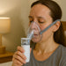 Woman using a nebulizer mask with a white background