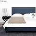 Bed with beige comforter and dark blue headboard, nightstand with lamp on a white background, Dr. Odin brand visible.