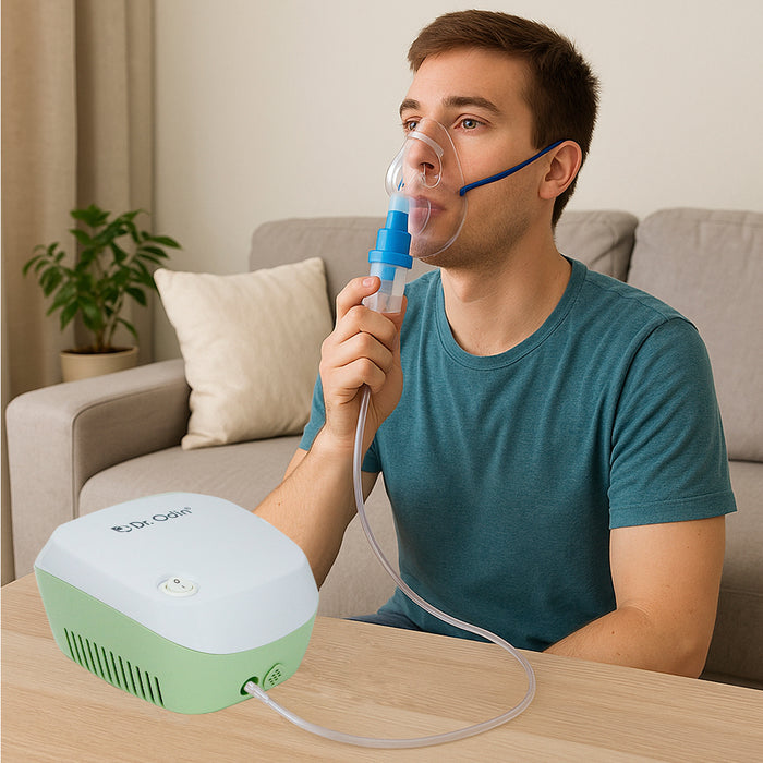 Man using an inhaler device with a green and white machine on a table in a living room setting.