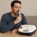 Man using an inhaler with a Dr. Odin device on a wooden surface.