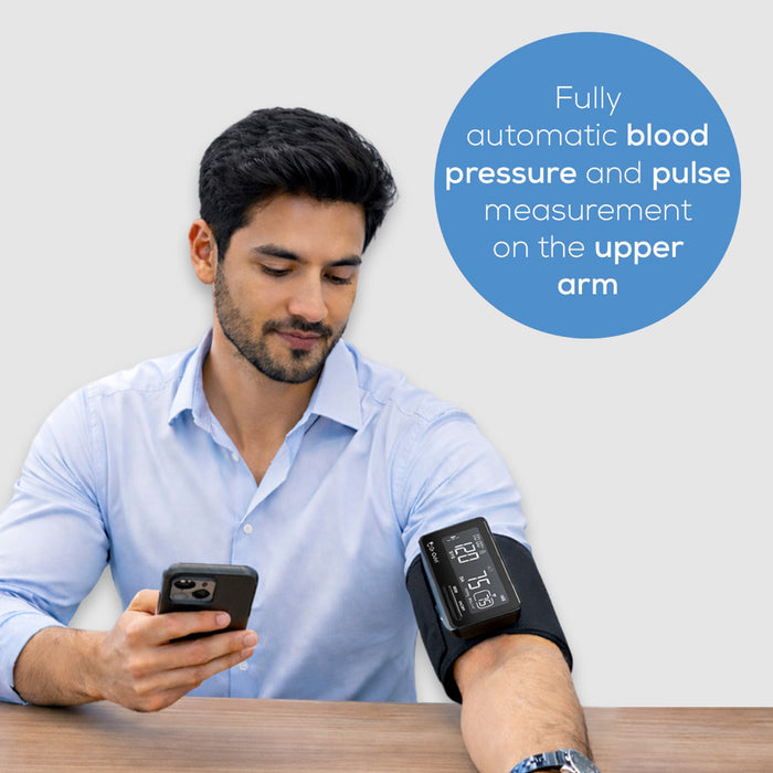 Man using a blood pressure monitor on his arm with text about measurement location.