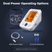 Blood pressure monitor with USB power input, batteries, and adapter on a dark background